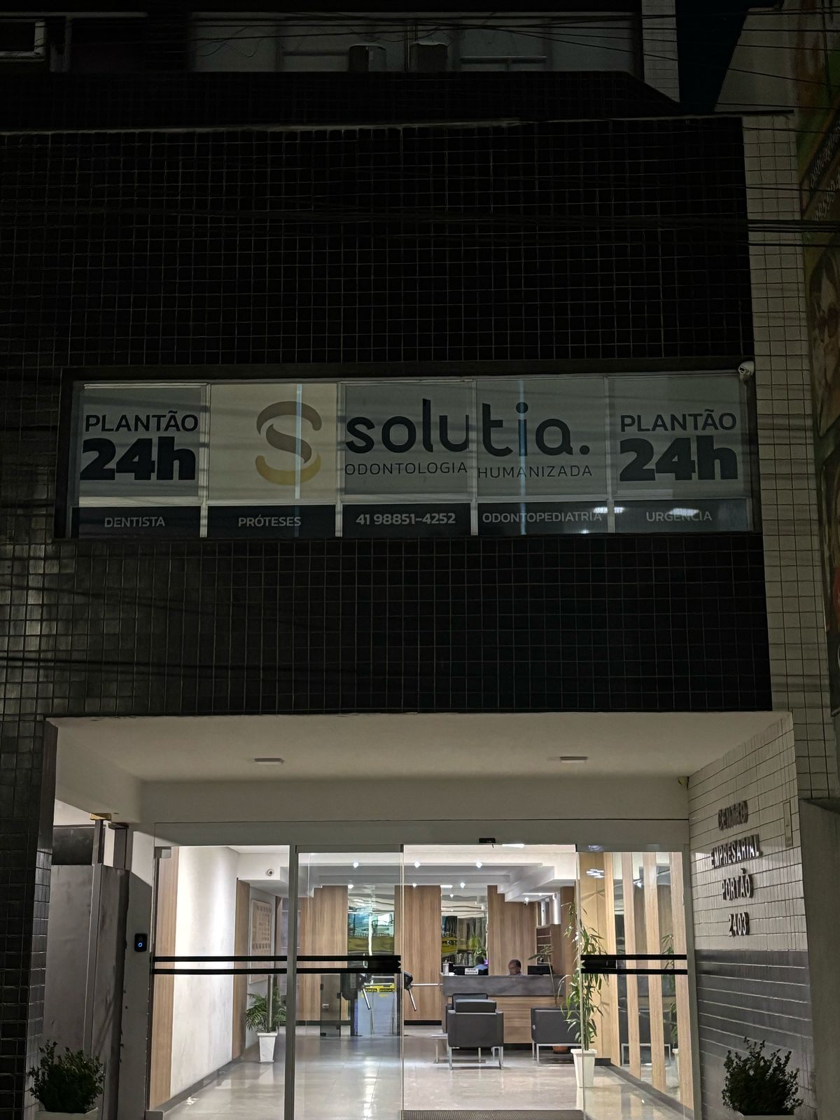 Fachada da Solutia à noite, com a placa Plantão 24h acesa